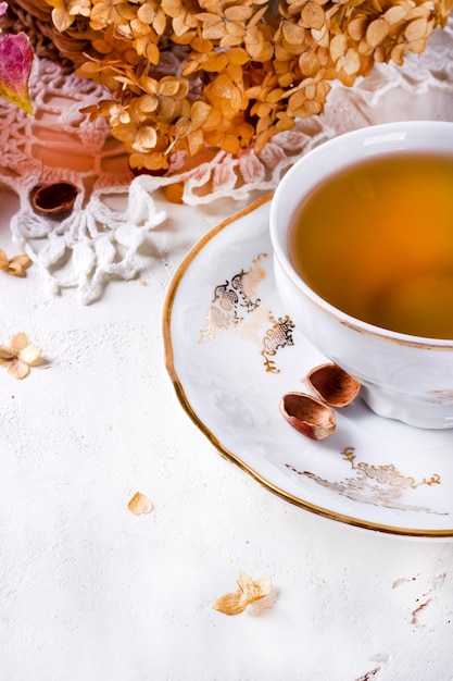 Photo tea in the rustic vintage chic style. garden tea party. teapot of dry flowers. cup of tea with autumn decor on table, with hydrangea and pumpkin