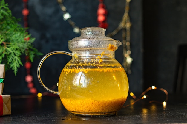 Tea sea buckthorn in a teapot and in a transparent cup on the table