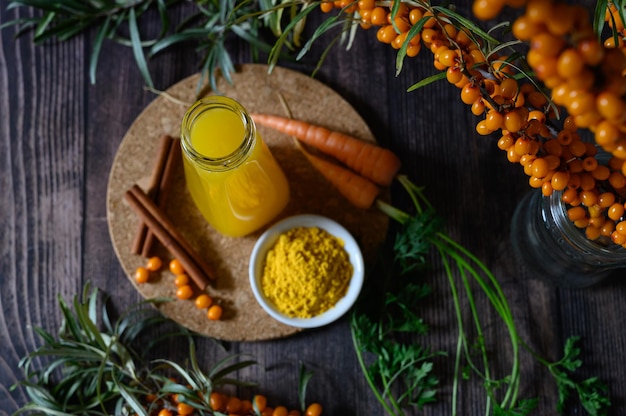 Tea of seabuckthorn berries with branch on dark wooden background