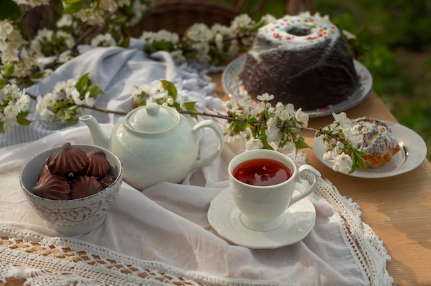 晴れた日の桜の枝に白いテーブルクロスにお茶をセット