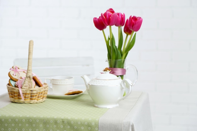 明るい背景のテーブルに花とお茶セット