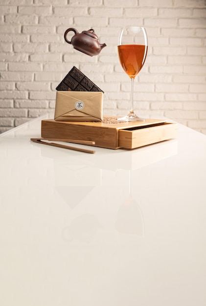 Чайный столик с чаем и фужер, в который налит чай Шэн Пуэр для демонстрации цвета