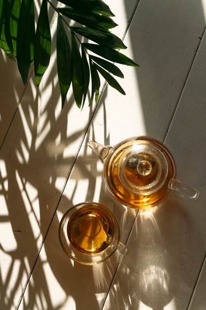 背景の太陽の下でティーポットのお茶をクローズアップ