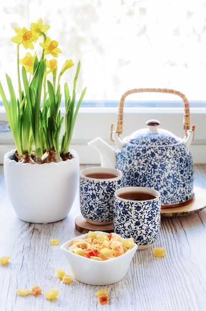 Tea time een theeservies met kleine blauwe patronen gekonfijte vruchten narcissen in een witte keramische vaas foto