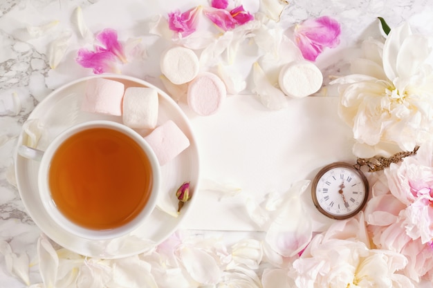 Tea time. Flat lay with peonies, marshmalows and cup of tea
