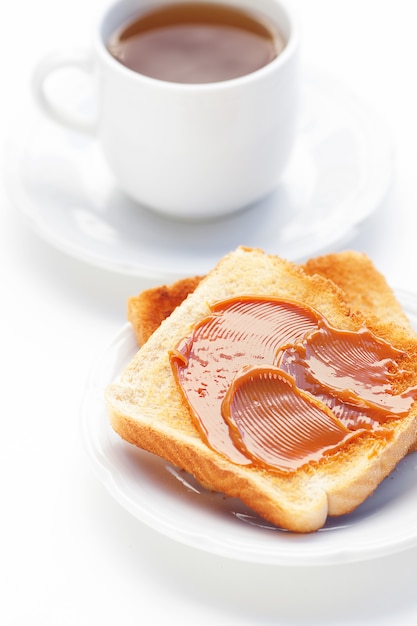 Foto tè e pane tostato con caramello isolato su bianco