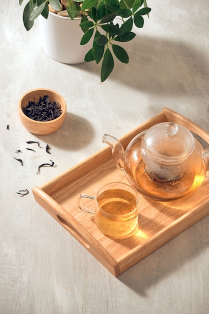 Tea in a transparent cup and teapot on a wooden background