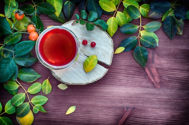 Tea in a transparent glass mug among the leaves 