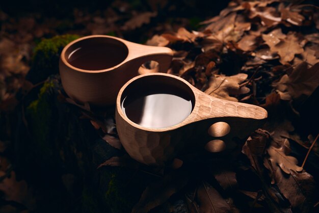 Tea in a two wooden national mugs Kuksa in the autumn forest at night