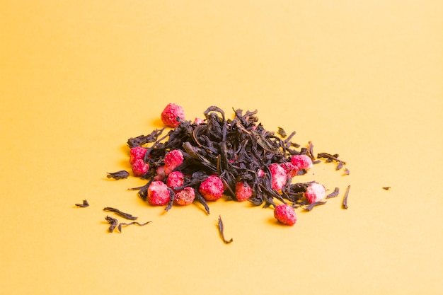 tea with dry strawberries on a yellow background