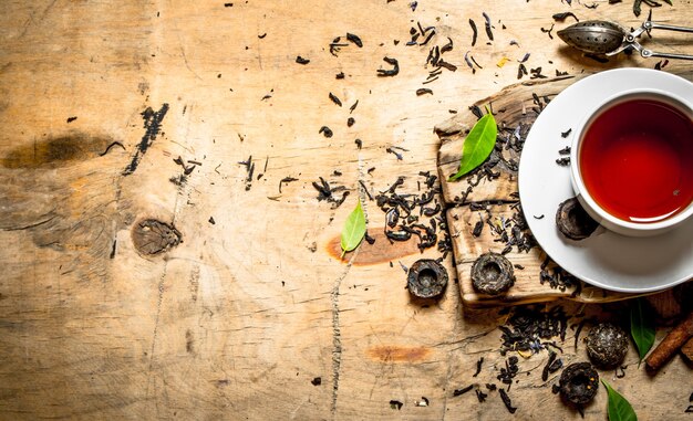 Tea with leaves and cinnamon. On wooden table.