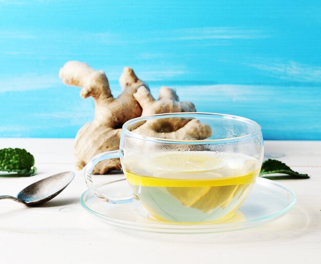 Tea with lemon and mint in a glass container in the background 