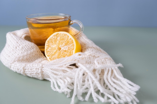 Чай с лимоном в белом шарфе стоит на сером столе