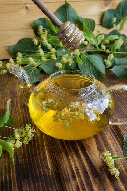 Tea with linden flower in the glass teapotn on the wooden background Closeup Location vertical