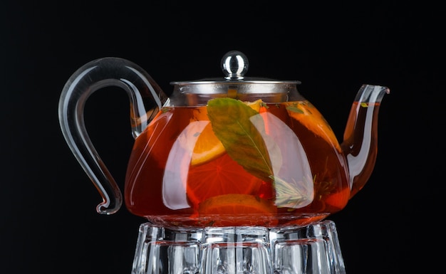 Фото Чай с мятой и лимоном в прозрачном чайнике на черном фоне. изолированные
