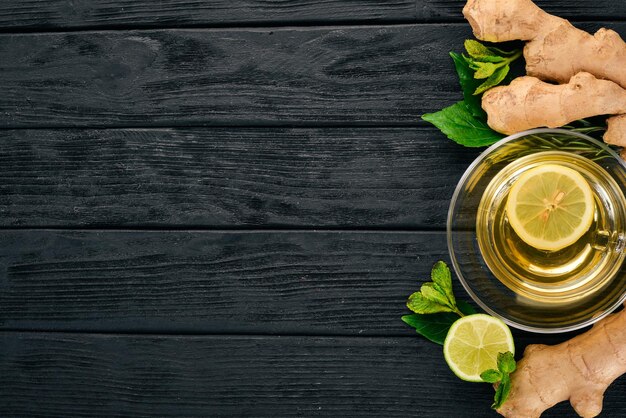 Tea with mint, ginger and lemon. Hot drink On a wooden background. Top view. Copy space.
