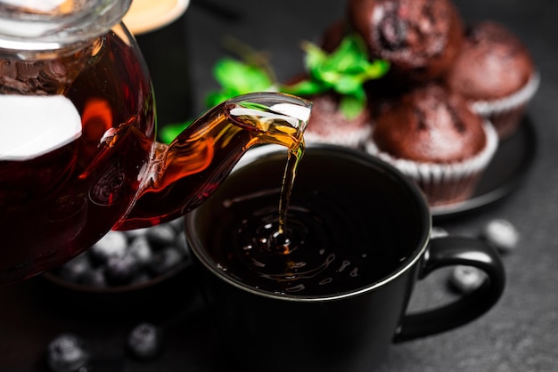 Tea with muffins on a dark background Chocolate muffins with blueberries