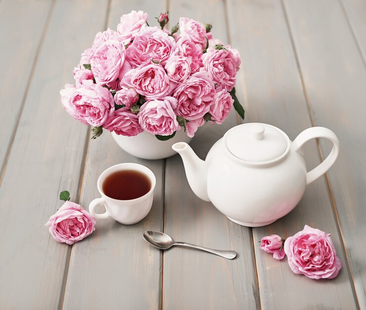 Tea with pink roses on grey wooden table, copy space.