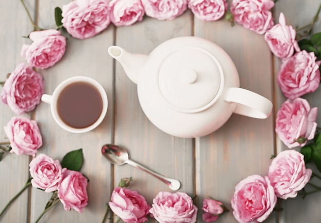 Photo tea with pink roses on grey wooden table, copy space.