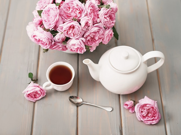 Фото Чай с розовыми розами на сером деревянном столе, скопируйте космос.