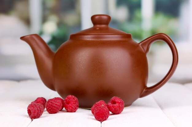 Tea with raspberries on table on bright background