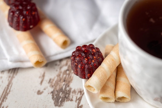 Tea with yummy raspberry marmalade sweets and wafer rolls