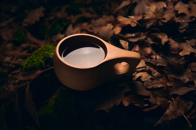 Чай в деревянной национальной кружке Кукса в осеннем лесу ночью