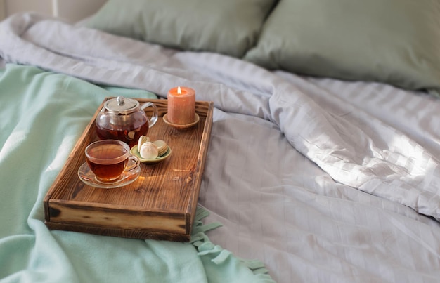 Tea on wooden tray on bed at home