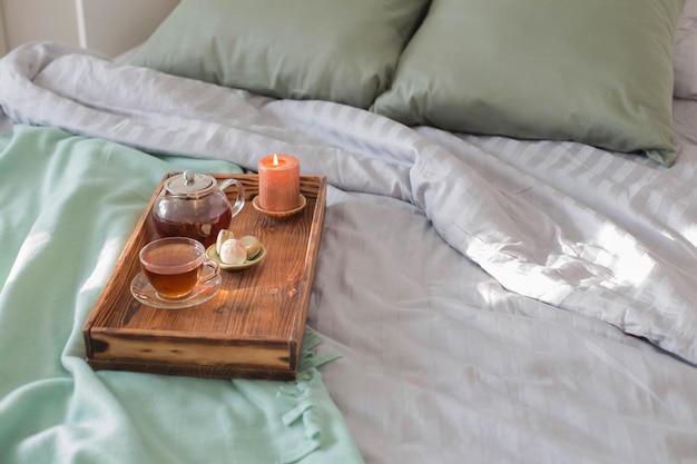 Photo tea on wooden tray on bed at home