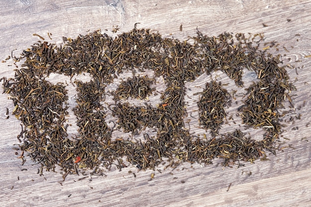 Tea word made of green tea leaves on wooden background