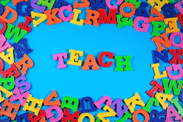 Teach written by plastic colorful letters on a blue background