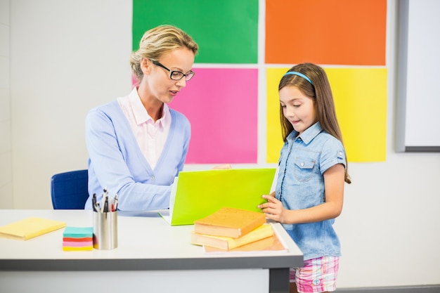 Teacher assisting schoolgirl in drawing