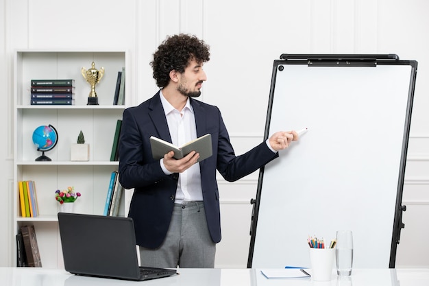 Teacher brunette instructor with computer in suit and whiteboard in classroom holding marker