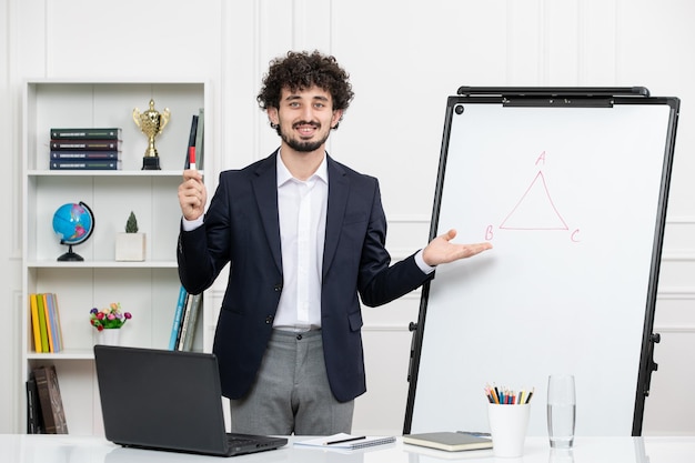 Teacher brunette instructor with computer in suit and whiteboard in classroom smiling