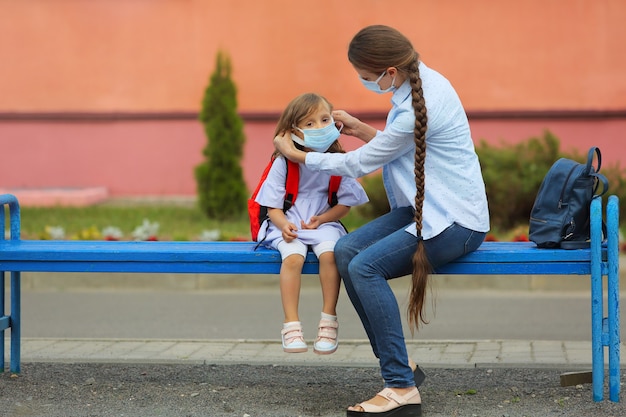 Воспитатель проверяет и помогает девочке правильно надеть маску, чтобы не допустить коронавируса.