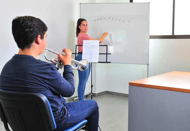 Teacher corrects music in the classroom, to a young student