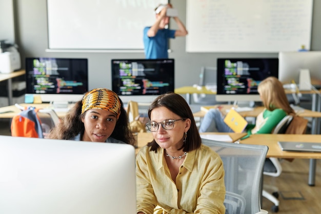 Teacher discussing presentation with student on computer during IT lesson