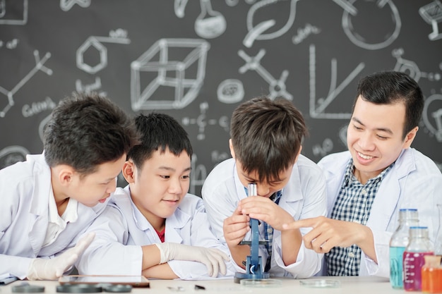 Teacher encouraging courious students to look at petri dish through microscope