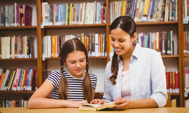 Teacher and girl reading book in library