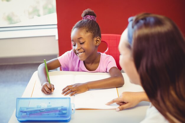 Photo teacher helping a girl with her homework in classroom