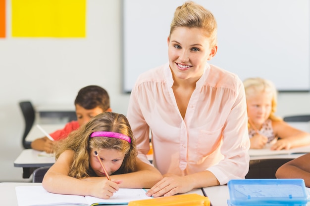 Teacher helping kids with their homework in classroom