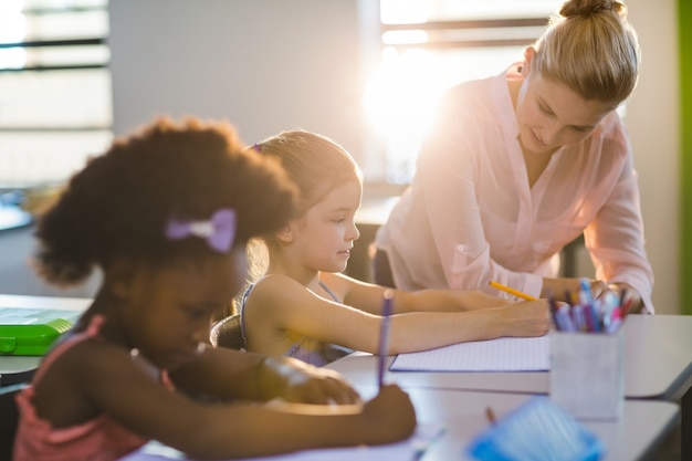 Insegnante aiutare i bambini a fare i compiti in classe