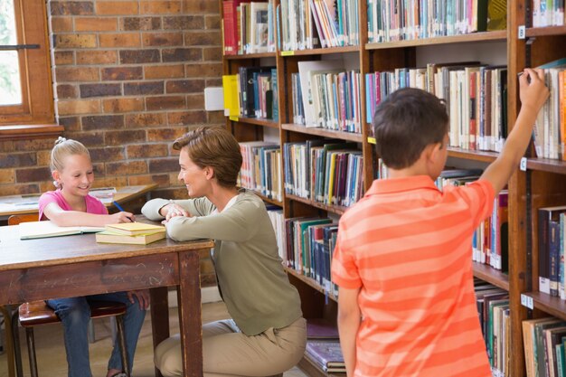 Photo teacher helping pupil in library