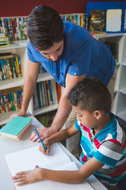 Учитель помогает школьнику с домашним заданием в библиотеке