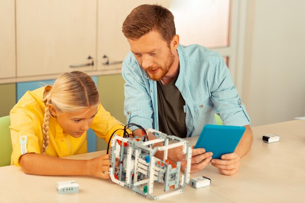 Teacher helping a schoolgirl building a robot