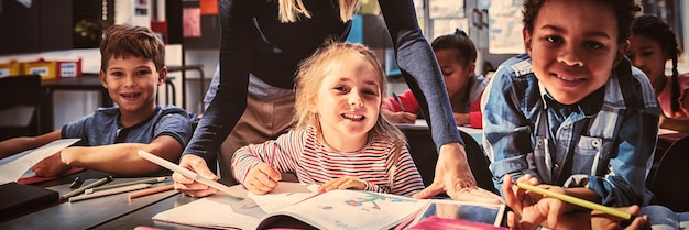 Teacher helping schoolkids with their homework in classroom