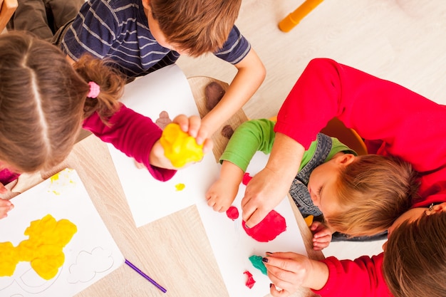 The teacher helps the boy to make a figure plasticine on the table