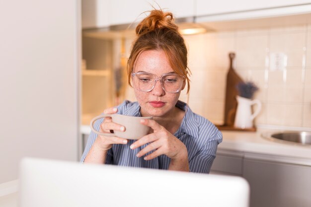 Teacher at home drinking tea and listening to students during online class