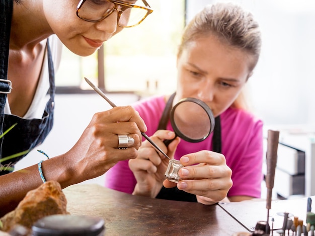 Teacher jeweler and student make jewelry in workshop