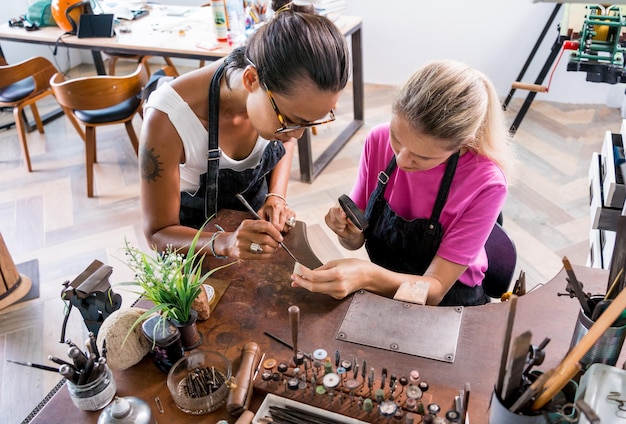 Teacher jeweler and student make jewelry in workshop